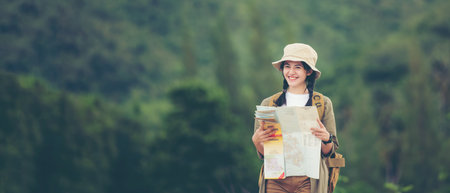 Asian young women holding map for check location adventure, tourism for destination leisure trips for education and relax in outdoors forest nature. Travel vacations and Life Concept, copy space for bannerの写真素材