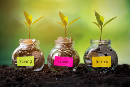 Plant growing in Coins glass jar on dry with investment  for Travel Retire Saving paper label for money planning travel and retirement. Green nature backgroundの写真素材