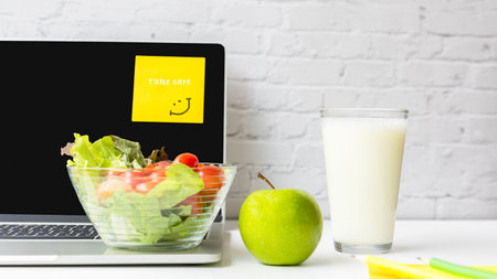 Healthy snack with working in the office.  Green apple and fresh salad with milk for diet Health life with laptop on white dress working, write take care on post it background.  Healthy Lifestyle Conceptの写真素材