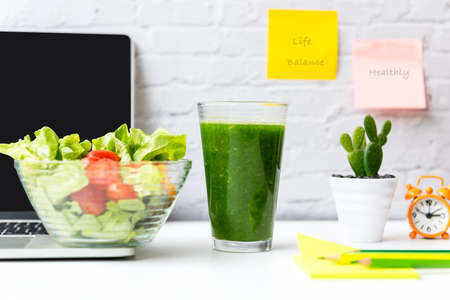 Healthy snack with working in office.  Green apple, fresh salad and vegetable smoothie for diet Health with laptop and supplier office on white dress working, write  life balance and healthy on  background.  Healthy Lifestyle Conceptの写真素材