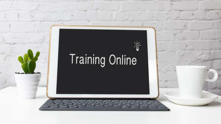 Training courses Online text on laptop screen on table with coffee cup at home. Technology and Education Conceptの写真素材