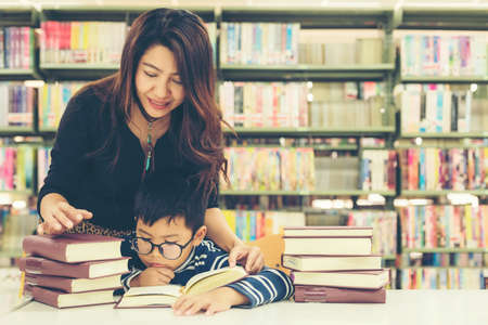 Schoolboy reading books for education and go to school with the guidance of his teacher in library . Education and Lifestyle Conceptの写真素材