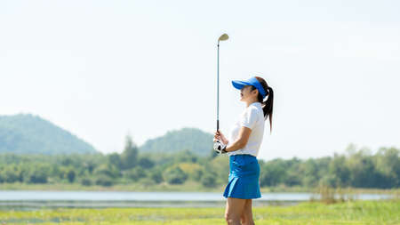 Golfer women sport course golf ball fairway. People lifestyle woman playing game golf tee of on the green grass sunset background. Asia female player game shot in summer. copy space bannerの写真素材