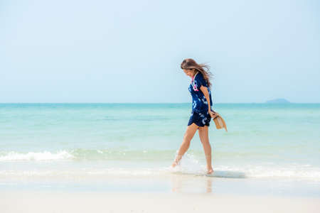 Summer vacations. Lifestyle woman relax and chill on beach background.  Asia happy young people walking on the wave sea, summer trips enjoy  tropical beach. Lifestyle and Travel Concept.の写真素材