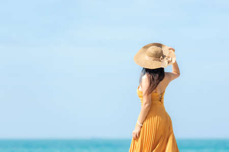 Summer vacations. Lifestyle woman relax and chill on beach background.  Asia happy young people wearing yellow dress fashion summer trips walking enjoy  tropical beach. Lifestyle and Travel Concept.の写真素材