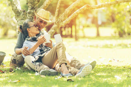 Asian Lifestyle senior couple hug and sitting in the nature park happy in love romantic and relax...