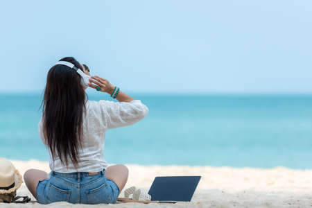 Lifestyle freelance woman listen music after using laptop working and relax on the beach.Â  Asia...