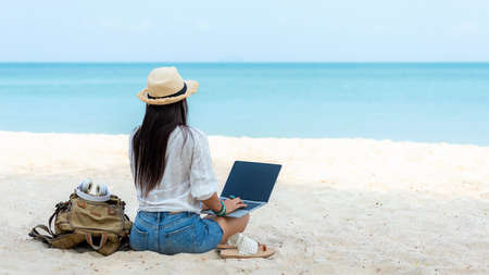 Lifestyle freelance woman using laptop working and relax on the beach.Â  Asia people success and together your work pastime and meeting conference on internet in holiday. Business and Summer Conceptの写真素材