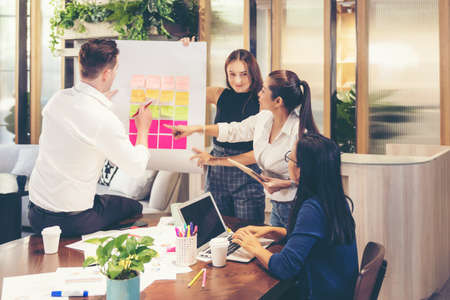 Business people meeting use sticky notes on whiteboard in office.  Teamwork diverse employees people group planning work together and success brainstorm strategy.の写真素材