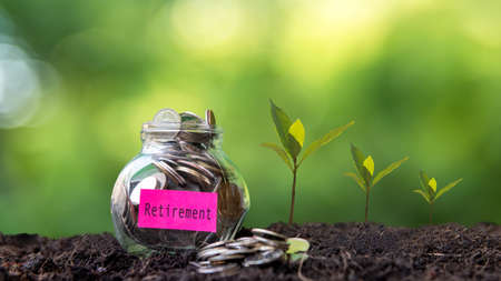 Plant growing in Coins glass jar on dry with investment  for Travel Retire Saving paper label for money planning travel and retirement. Green nature backgroundの写真素材