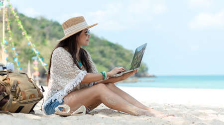 Lifestyle freelance woman using laptop working and relax on the beach.Â  Asian people success and together your work pastime and meeting conference on internet in holiday. Business and Summer Conceptの写真素材