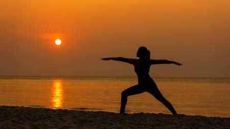 Silhouette lifestyle woman yoga exercise for healthy life.Â  Young girl or people pose balance body vital zen and meditation workout and fitness sport outdoor sunset near the beach. Sea background. Health care Conceptの写真素材