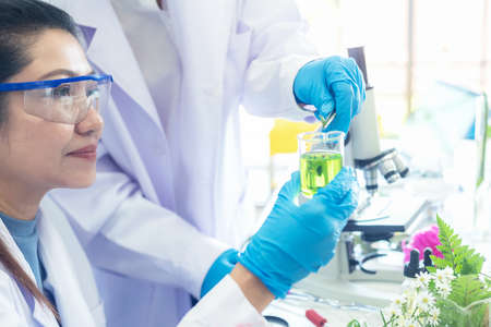 Asian Woman and team science lab research for Natural alternative herb and essential oil from fresh flower new product skin care with microscope.  Healthy  Laboratoryの写真素材