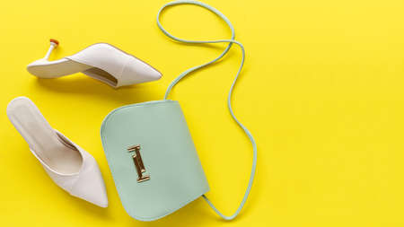 Fashion green bag and white shoes woman accessories on yellow color background. Trendy fashion...