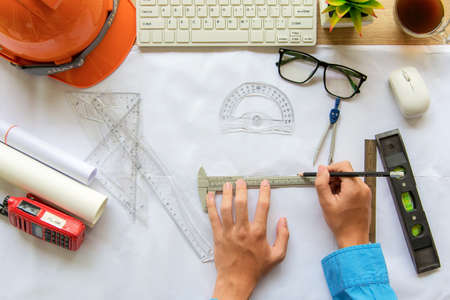 Top View Architect working on blueprint. Architects workplace. Engineer tools and safety control, blueprints, ruler, radio, laptop and divider compass. Construction Concept.の写真素材