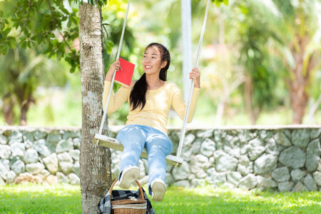Young people sitting swing and relax after working on laptop at nature garden home . Asia woman chill and resting in summer holiday.  Lifestyle Conceptの写真素材