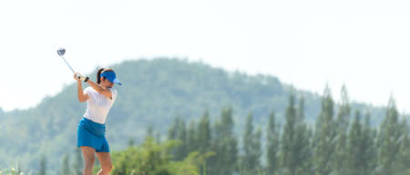 Golfer sport course golf ball fairway. People lifestyle woman playing game golf and hitting go on green grass and mountain background.Â  Asia female player game shot in summer.Â  Healthy and Sport outdoorの写真素材