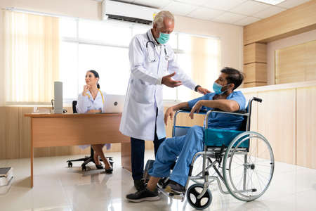 Team doctor explaining and discuss symptoms to patient.  Man patient sitting waiting treatment on wheel chair at hospital. Health Care Concept.の写真素材