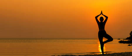 Silhouette lifestyle woman yoga exercise for healthy life.Â  Young girl or people pose balance body vital zen and meditation workout and fitness sport outdoor sunset near the beach. Sea background. Health care Concept, copy space for bannerの写真素材