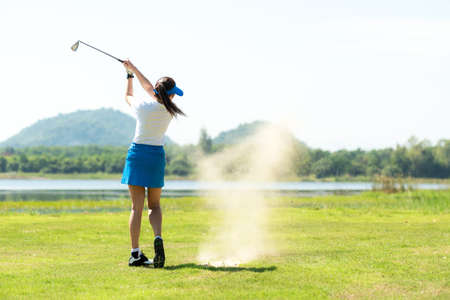 Golfer sport course golf ball fairway. People lifestyle woman playing game golf and hitting out of sand trap go on green grass.Â  Asia female player game shot in summer.Â  Healthy and Sport outdoorの写真素材