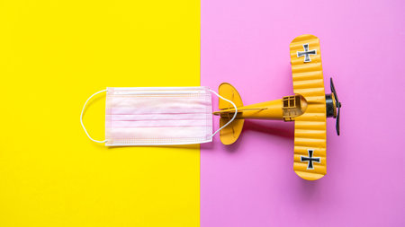 Airplane and medical mask on pastel background. Travel new normal and safety life.  Tourism observance of safety on the plane. Traveling by air with medical advice on travel in holiday.  protect covid-19の写真素材