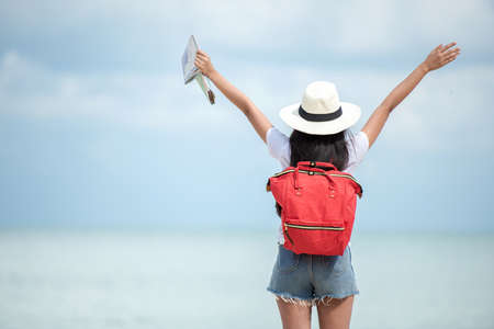 Happy traveler and tourism women travel summer on the beach.Â  Asia people holding map and raise arm planning travel trip and relax outdoor for destination and leisure.Â  Summer Vacation Travel Conceptの写真素材