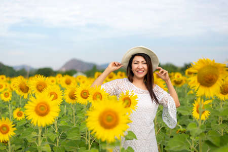 Tourism Asia woman standing relax chill in the sunflower field in vacations time.  People  freedom and enjoy in the spring meadow.  Lifestyle Conceptの写真素材