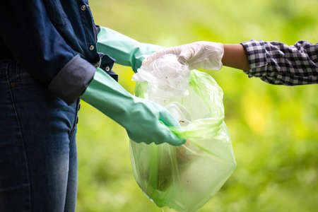 Close up hand children collecting garbage and plastic on the river to dumped into the trash for volunteer charity save environment. Ecology earth Conceptの写真素材