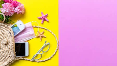 Traveler accessories medical face mask , hand gel sanitizer protect in hand bag, pink yellow background. Tourism backpack and visiting for planning airplane trips travel destination and vacations. Top view and copy space for text.の写真素材
