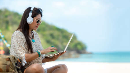 Lifestyle freelance woman using laptop working and relax on the beach.Â  Asian people success and together your work pastime and meeting conference on internet in holiday. Business and Summer Conceptの写真素材
