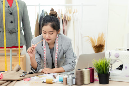 Work from home. Asian young woman fashion designer  working on her design in the showroom.  Lifestyle people Stylish tailor taking measurements on mannequin in studio.  Business small Conceptの写真素材