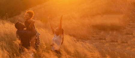 Soft focus. Happy African family father mother and child daughter travel and running on meadow nature on silhouette lights sunset.  Travel and Family Concept, copy space for bannerの写真素材