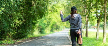 Healthy woman warming up before jogging run and relax stretching her arms and looking away in the road outdoor. Asian runner people workout fitness session, nature park background. copy space for bannerの写真素材