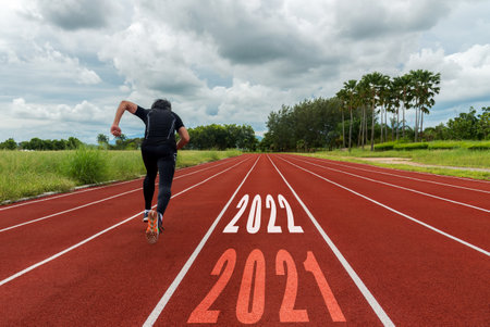 The start into the new year 2022. Start up of runner man running on race track go to Goal of Success.  People running as part of Number 2022.  Holiday sport and health care Conceptの写真素材