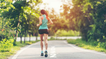 The start into the new year 2022. Start up of runner woman running on nature race track go to Goal of Success.  People running as part of Number 2022.  Holiday sport and health care Conceptの写真素材