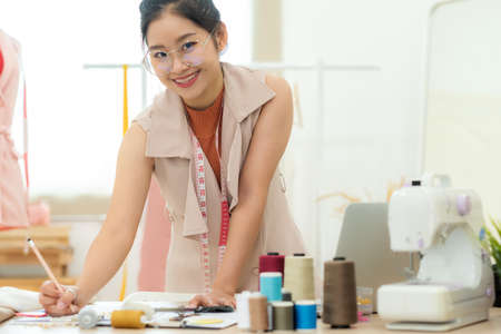 Owner business asian young women fashion designer working on her designer in the showroom,  Lifestyle Stylish tailor taking measurements on mannequin in studio.  Business and Industry small Conceptの写真素材