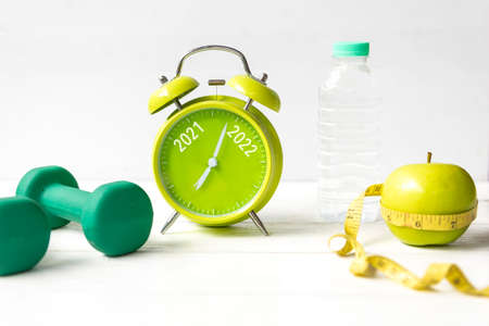 2021 and 2022 on alarm clock with workout planing for dieting. Sport exercise equipment workout andÂ gym nutrition for fitness. Merry Christmas and Happy new year conceptの写真素材