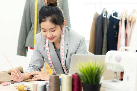 Asian young women fashion designer  working on her designer in the showroom,  Lifestyle Stylish tailor taking measurements on mannequin in studio.  Business small Conceptの写真素材