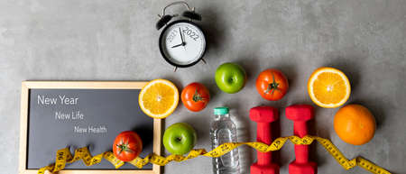 2021 and 2022 on alarm clock with workout planing for dieting. New Year New Life and New Health,  Sport exercise equipment workout andÂ gym nutrition fresh fruits for fitnessの写真素材