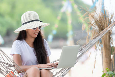 Lifestyle freelance woman using laptop working and relax on the beach.Â  Asian people success and together your work pastime and meeting conference on internet in holiday. Business and Summer Conceptの写真素材