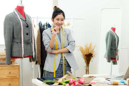 Asian young women fashion designer  working on her designer in the showroom,  Lifestyle Stylish tailor taking measurements on mannequin in studio.  Business small Conceptの写真素材