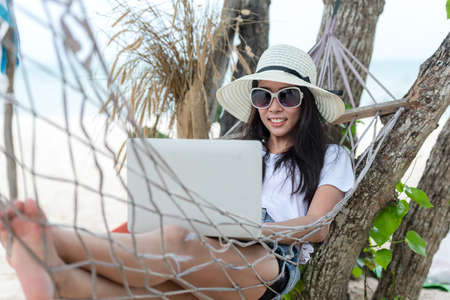Lifestyle freelance woman using laptop working and relax on the beach.Â  Asian people success and together your work pastime and meeting conference on internet in holiday. Business and Summer Conceptの写真素材