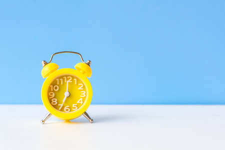 Alarm yellow vintage alarm clock falling on the floor with blue color background, copy space for tex.  Morning and Start up Conceptの写真素材