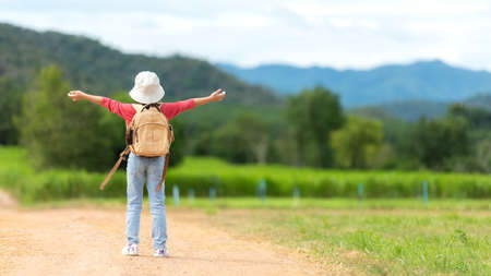 Asian girl raise arms on road with  green meadow outdoors adventure. People kid tourism  traveling education nature forest for destination and leisure trips with mountain.Â  Travel vacations and Life Conceptの写真素材