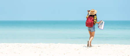Happy traveler and tourism young women travel summer on the beach.Â  Asian people holding camera take photo  and relax outdoor destination and leisure trip travel in holiday.Â  Copy space for bannerの写真素材