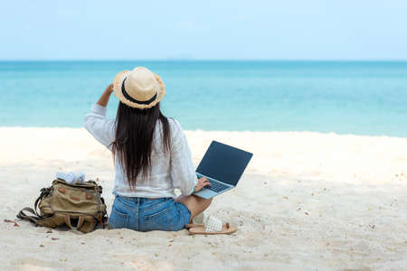 Lifestyle freelance woman  using laptop working and relax on the beach.Â  Asian people success and together your work pastime and meeting conference on internet in holiday. Business and Summer Conceptの写真素材