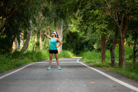 Healthy woman jogging run and workout on road outdoor. Asian runner people exercise gym with fitness session, nature park background. Health and Lifestyle Conceptの写真素材