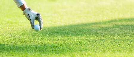 Close up hand asian sporty woman putting golf ball on tee with club in golf course on evening on time for healthy sport. Banner and copy space for text.  Lifestyle and Sport Conceptの写真素材