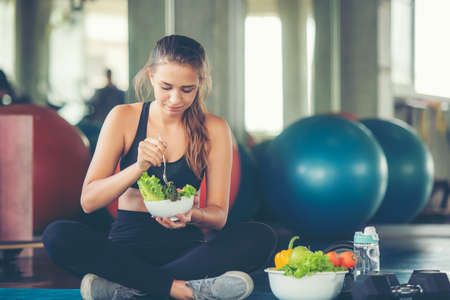 Healthy lifestyle woman fitness gym for body slim. Young people girl hold fresh salad after exercise. Fitness instructor exercising the fitness. Diet and Healthy sport Conceptの写真素材