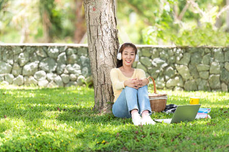 Young people work from home with laptop and listing music in morning relax at nature garden home. Asia woman meeting conference connect online with office.  Lifestyle Conceptの写真素材